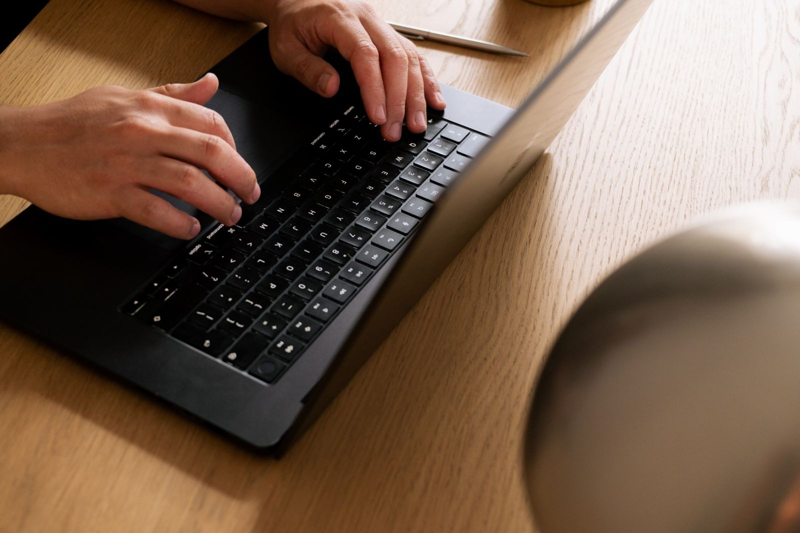 Hands typing on a laptop at a wooden desk